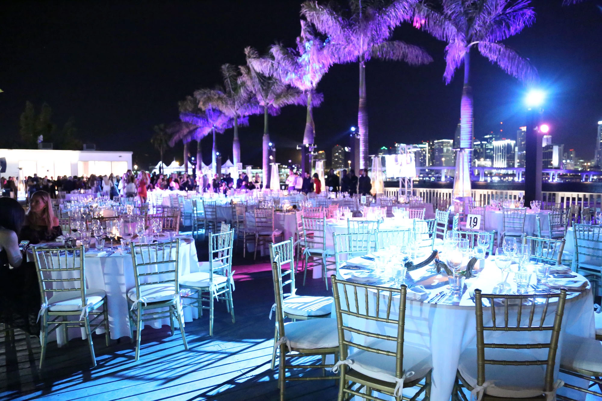 photo of tables outside by palm trees at night